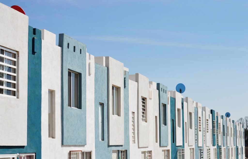 Abwechselnd blaue und weiße quadratische Häuserfronten mit Fenstern und Gittern